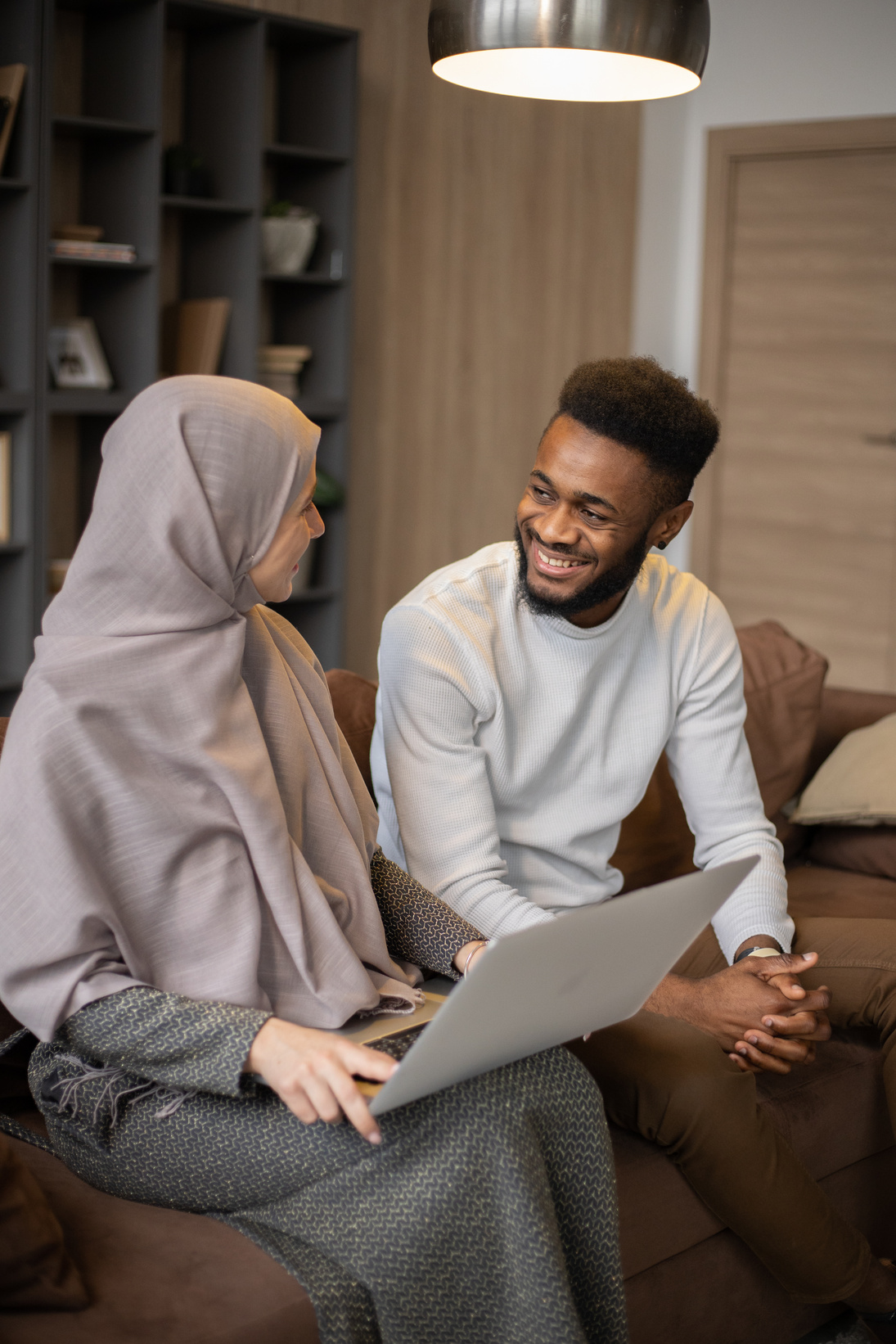 Cheerful diverse couple with laptop on couch